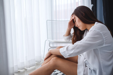 Wall Mural - A sad and stressed young asian woman sitting alone in bedroom