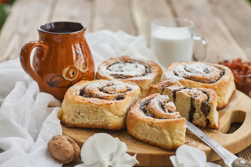 Wall Mural - Basket of homemade buns with jam, served on old wooden table with walnuts and cup of milk