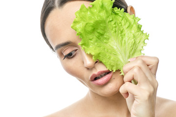 Wall Mural - portrait of a girl with clean skin without makeup with a leaf of green salad