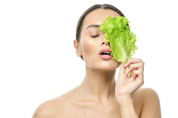 Wall Mural - portrait of a girl with clean skin without makeup with a leaf of green salad