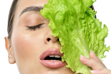 Wall Mural - portrait of a girl with clean skin without makeup with a leaf of green salad