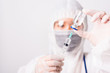 © sorapop - Closeup hand of woman doctor or scientist in PPE suite uniform wearing face mask protective in lab hold medicine liquid vaccine vial bottle and syringe, coronavirus or COVID-19 concept white isolated