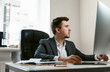 © ANR Production - Thoughtful businessman at office workplace is typing text on a desctop computer keyboard. The idea of a new successful project. Financial analyst or IT specialist, sales manager, freelancer.