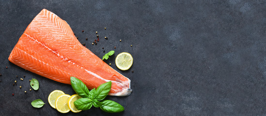 Raw salmon filet on a black background with lemon and basil.Flatly food.