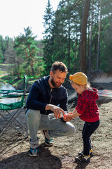 Wall Mural - a man helps to wash the hands of a little girl in the forest, camping, travel, tourism, hike and people concept - concept happy family camping in the forest