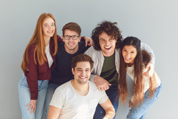 Group of young people in casual clothes smiling while gray background.