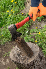 Hands hold an ax and chop wood on a stump