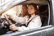 © Vlad - Driving instruction. A young woman learns to drive a car for the first time. Her instructor or boyfriend helps her and teaches her