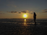 Fototapeta  - man walking on the beach at sunset