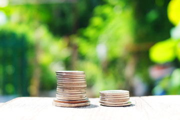 Money coins on wooden floor in green natural bokeh background for Saving and growing in success economy and bussiness life concept.