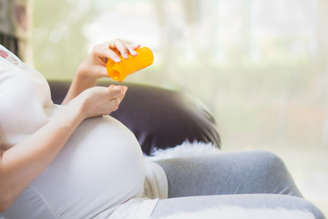 Close up unidentified pregnant woman's hand is taking the the pill from the bottle, concept of healthcare ,risk and precaution of use the medicine in pregnancy woman and risk to the baby.