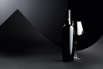 Sticker - Bottle and glass of red wine on a dark background.