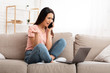 © Prostock-studio - Frustrated woman talking on mobile phone sitting on sofa