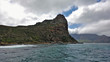 © Вера  - Severe cliffs in the cold atlantic ocean. Steep rocky slopes are covered with sparse shrubs. The waves beat against the shore. Dense picturesque clouds lie on the tops of the mountains. South Africa.