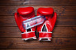 Red boxing gloves with bottle of water on wooden background