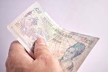 Cropped Image Of Hand Holding Five Pound Note Against White Background