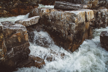 Wall Mural - Stream of river among stones and rocks. Stream in stone bed, fast mountain river among rocks, water boils in eddies of current