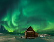 Landscape with northern lights over a wooden house on the coast of the Barents Sea on the Kola Peninsula at night at high ISO sensitivity