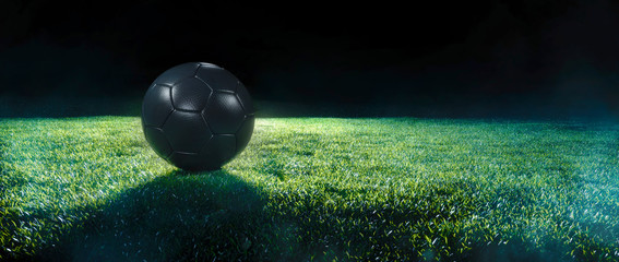 Poster - Black Football on an illuminated empty sports field at night.