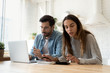 © fizkes - Concentrated young couple sit at desk in kitchen pay bills on computer online calculate finances together, millennial husband and wife manage household expenses use Internet banking system on laptop