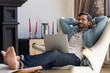 © fizkes - Happy millennial man sit relax in comfortable design armchair in living room take nap distracted from computer work, smiling young male rest in chair at home breathe fresh air, stress free concept