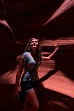 Young Woman Inside Upper Antelope Slot Canyon In Arizona Standing Holding Camera By Sandstone Formations Looking Up