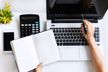 Wall Mural - Young Asian woman doing research work for her business with computer laptop while holding notebook at home, top view and copy space