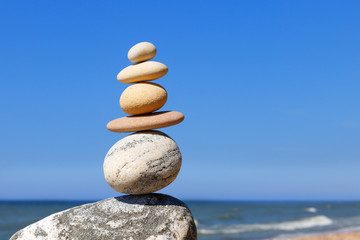 Wall Mural - Rock zen Pyramid of balanced stones against the background of the sea and blue sky.