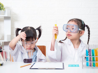 two little asian sibling girl role playing a scientist in science lab with equipment. learning and e