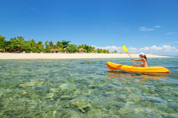 Wall Mural - Young woman kayaking near South Sea Island, Mamanuca islands group, Fiji