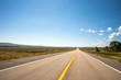 © Adam Hester - A point of view perspective of a vehicle traveling on a rural road with clouds and blue sky.