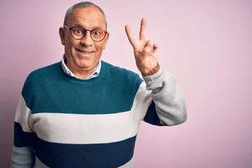 Wall Mural - Senior handsome man wearing casual sweater and glasses over isolated pink background smiling with happy face winking at the camera doing victory sign. Number two.