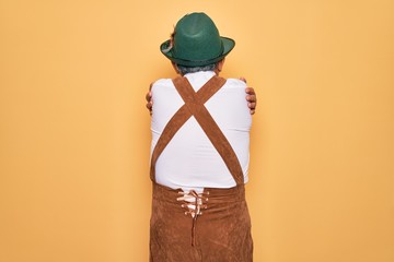 Sticker - Senior grey-haired man wearing german traditional octoberfest suit over yellow background Hugging oneself happy and positive from backwards. Self love and self care