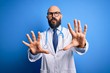 © Krakenimages.com - Handsome bald doctor man with beard wearing glasses and stethoscope over blue background doing stop gesture with hands palms, angry and frustration expression
