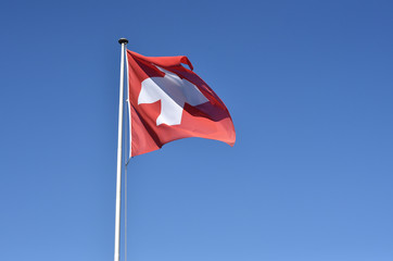 Swiss flag waving on blue sky