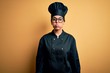 © Krakenimages.com - Young beautiful brunette chef woman wearing cooker uniform and hat over yellow background puffing cheeks with funny face. Mouth inflated with air, crazy expression.