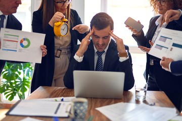 Group of business workers working together in a meeting. One of them surronded and stressed for partners at the office