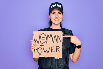 Canvas Print - Police woman wearing security bulletproof vest uniform holding woman power protest cardboard with surprise face pointing finger to himself