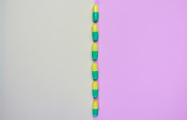 Wall Mural - Yellow-green capsules lie between two backgrounds of yellow and pink, dividing them in half.