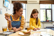 © Svitlana - Always there for baby care. African american woman baby sitter entertaining caucasian cute little girl. Kid is drawing while having lunch with her nanny. Leisure activities, babysitting concept