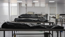 Covered Human Corpses On Tables In A Morgue / Mortuary Waiting For Identification, Autopsy, Burial Or Cremation. Taken In Armenia, Colombia.