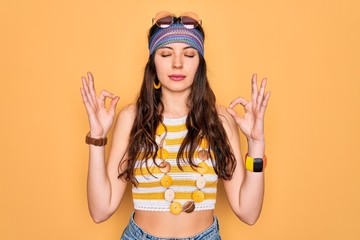 Wall Mural - Young beautiful hippie woman with blue eyes wearing accesories and sunnglasses relaxed and smiling with eyes closed doing meditation gesture with fingers. Yoga concept.