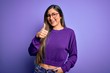 © Krakenimages.com - Young beautiful smart woman wearing glasses over purple isolated background doing happy thumbs up gesture with hand. Approving expression looking at the camera showing success.
