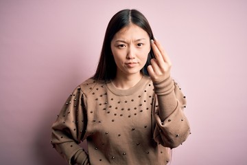 Poster - Young beautiful asian woman wearing fashion and elegant sweater over pink solated background Doing Italian gesture with hand and fingers confident expression