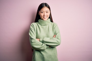 Wall Mural - Young beautiful asian woman wearing green winter sweater over pink solated background happy face smiling with crossed arms looking at the camera. Positive person.