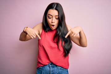 young brunette woman wearing casual summer shirt over pink isolated background pointing down with fi