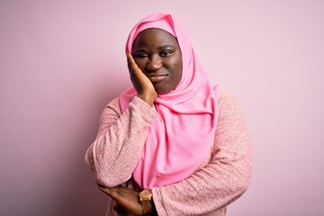 Poster - Young african american plus size woman wearing muslim hijab over isolated pink background thinking looking tired and bored with depression problems with crossed arms.