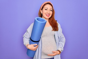 Poster - Young beautiful redhead pregnant woman expecting baby holding mat to do prenatal exercise with a happy face standing and smiling with a confident smile showing teeth