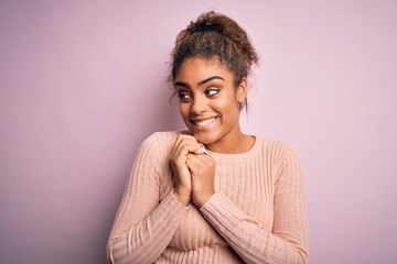 Canvas Print - Young beautiful african american girl wearing casual sweater standing over pink background laughing nervous and excited with hands on chin looking to the side