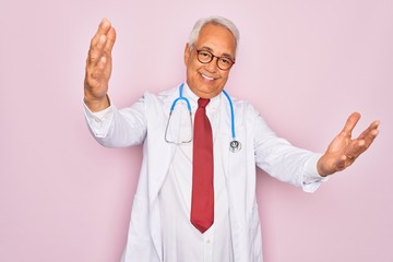 Wall Mural - Middle age senior grey-haired doctor man wearing stethoscope and professional medical coat looking at the camera smiling with open arms for hug. Cheerful expression embracing happiness.